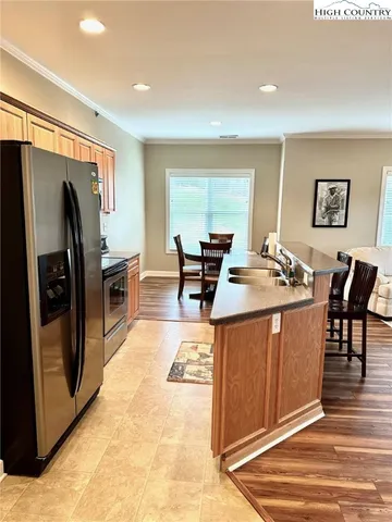 a kitchen with stainless steel appliances granite countertop a refrigerator a stove and a dining table with wooden floor