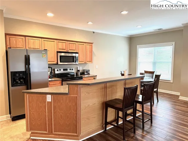 a kitchen with stainless steel appliances granite countertop a refrigerator a stove a sink a dining table and chairs