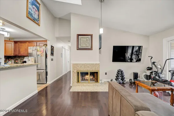 a living room with stainless steel appliances furniture a fireplace a flat screen tv and a kitchen view