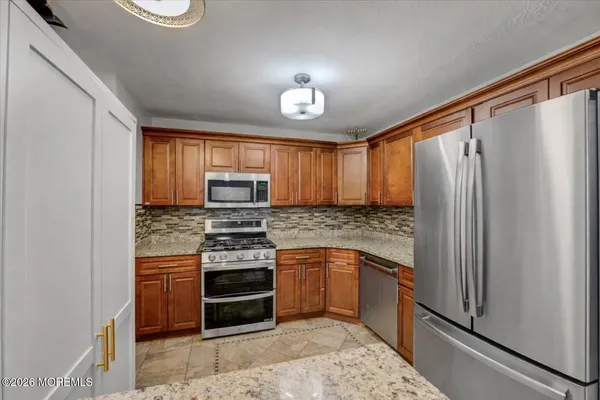 a kitchen with stainless steel appliances granite countertop a stove a refrigerator and a sink