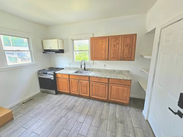 a kitchen with a sink wooden floor and a view of living room