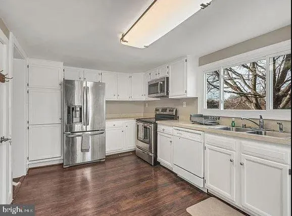 a kitchen with appliances cabinets a sink and a window