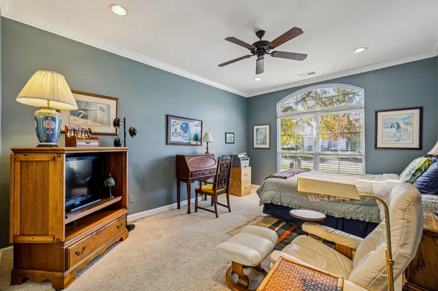 a bedroom with a bed a study table and large window