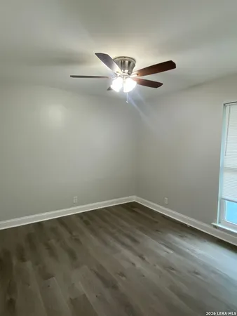 an empty room with wooden floor fan and windows