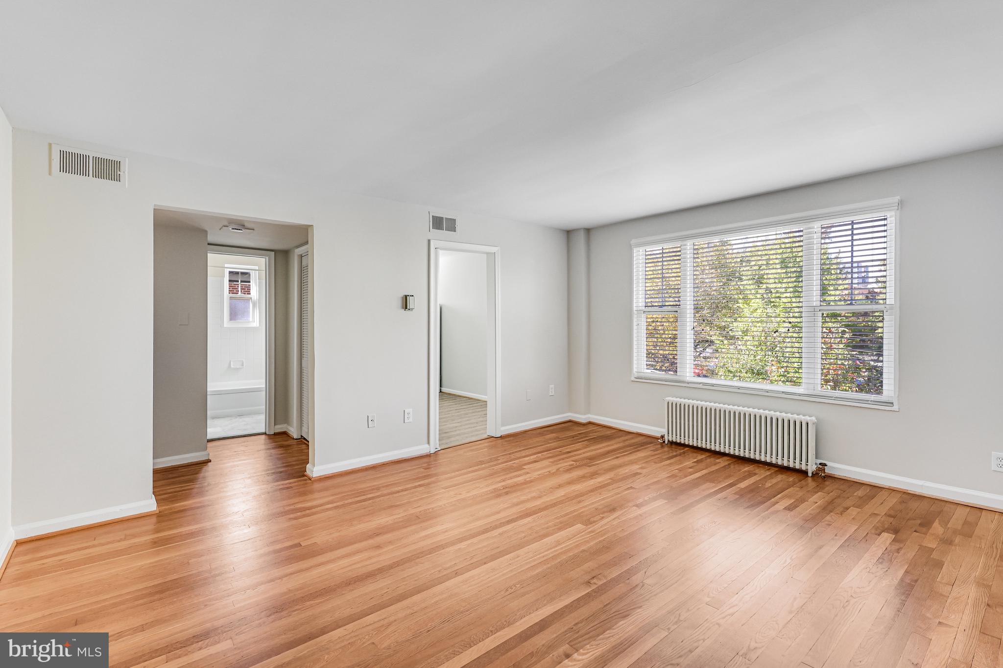 1404 12th Street North, Unit 32 Arlington, VA 22209 - Photo 6 of 26 a view of an empty room with wooden floor and a window