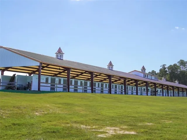 a view of a large pool with lawn chairs under an umbrella