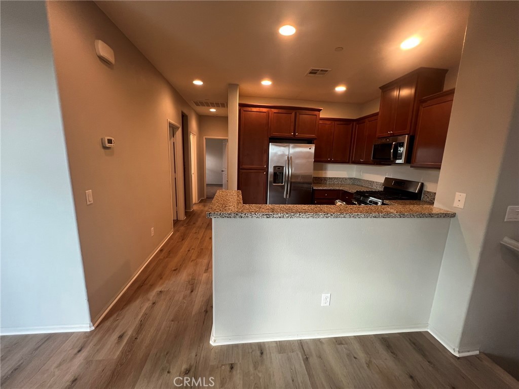 16001 Chase Fontana, CA 92336 - Photo 3 of 14 a view of kitchen with stainless steel appliances a refrigerator and wooden floor