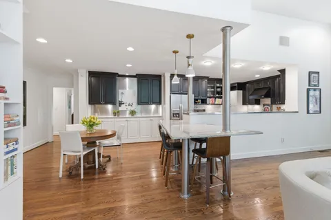 a kitchen with stainless steel appliances kitchen island granite countertop a table chairs and a refrigerator