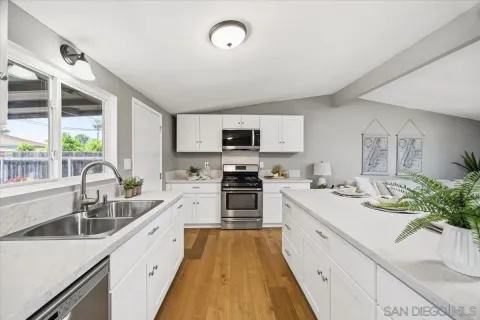 a large kitchen with a sink stainless steel appliances and cabinets