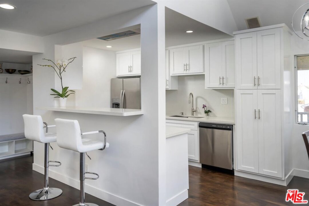 24 Westwind Street, Unit F Marina del Rey, CA 90292 - Photo 7 of 24 a kitchen with granite countertop white cabinets and chairs