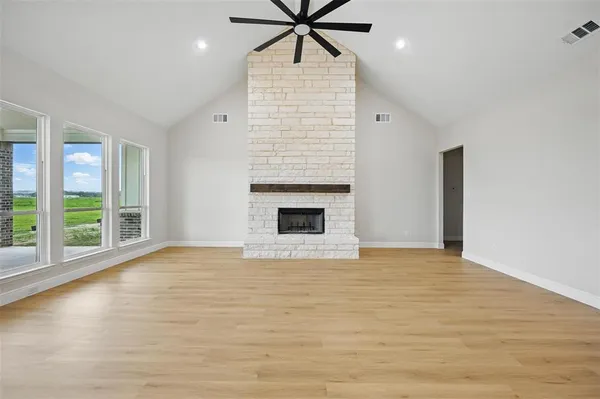 a view of an empty room with window and wooden floor