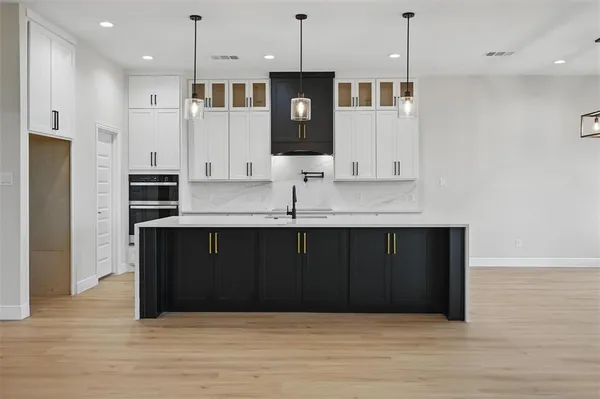 a kitchen with stainless steel appliances granite countertop a refrigerator a oven and a wooden floor