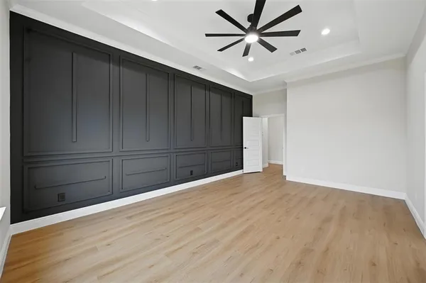 a view of an empty room with wooden floor kitchen view and a chandelier