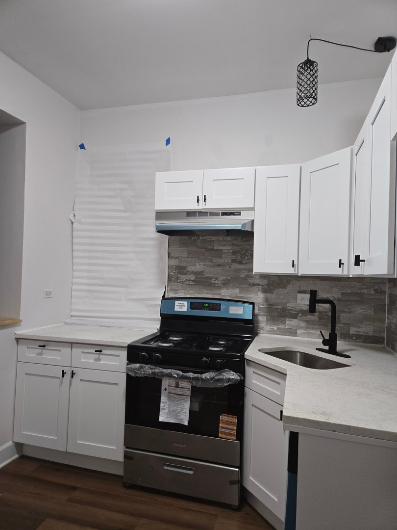 a kitchen with a stove and white cabinets