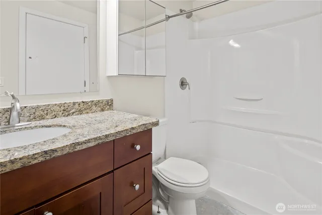 a bathroom with a granite countertop sink toilet and shower