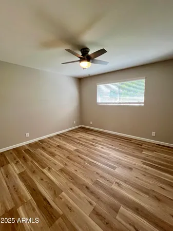 an empty room with wooden floor ceiling fan and windows