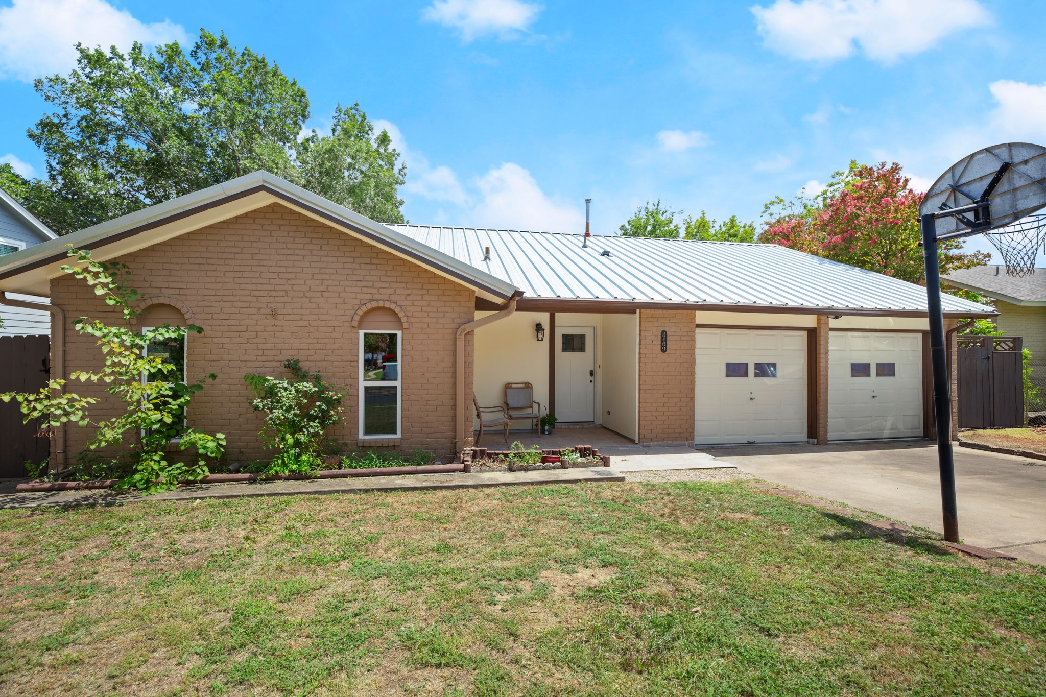 2109 Brandywine Lane Austin, TX 78727 - Photo 1 of 27 Ranch-style house with brick siding, an attached garage, a front lawn, driveway, and a metal roof