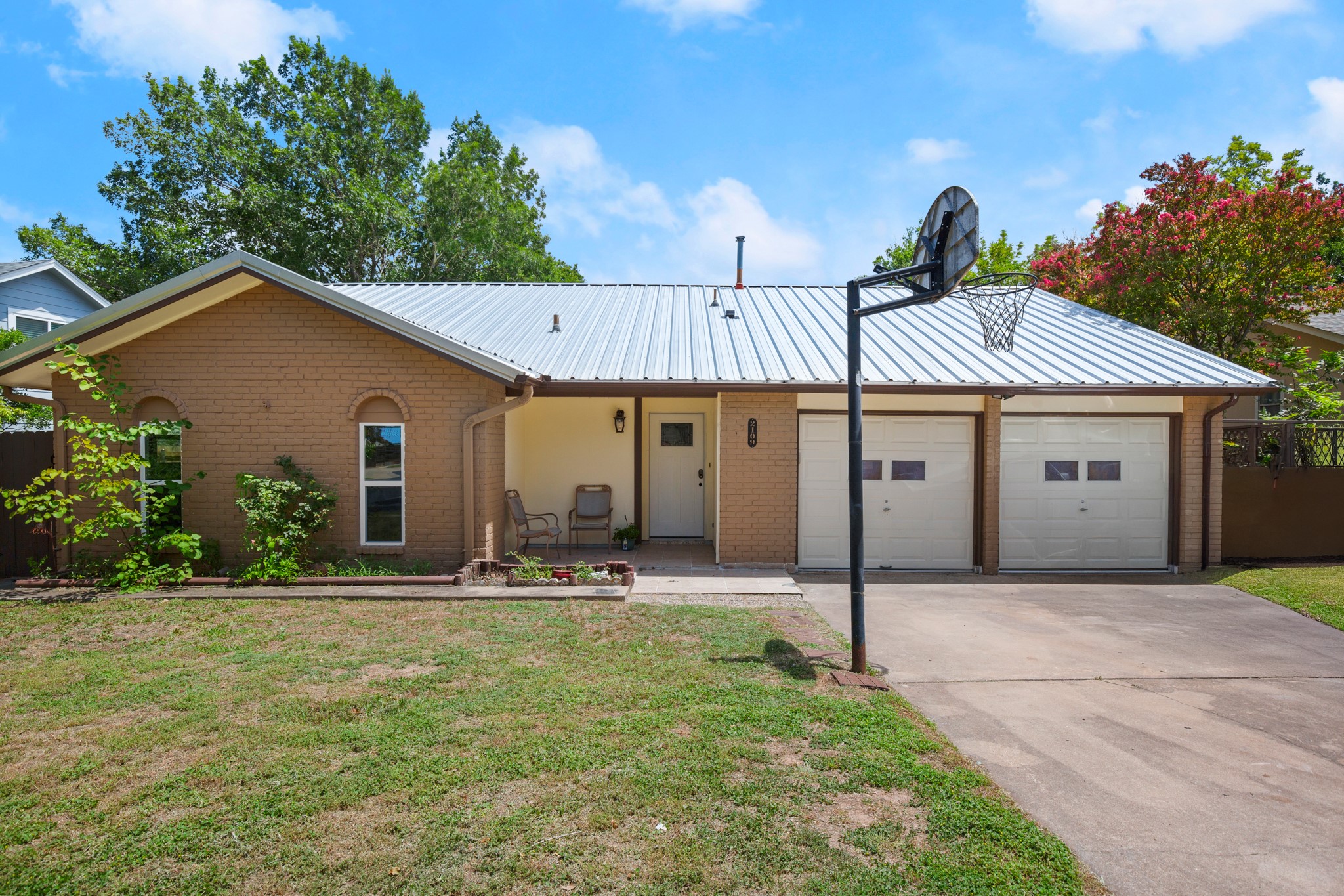 2109 Brandywine Lane Austin, TX 78727 - Photo 2 of 27 View of front of home with an attached garage, brick siding, concrete driveway, and a metal roof