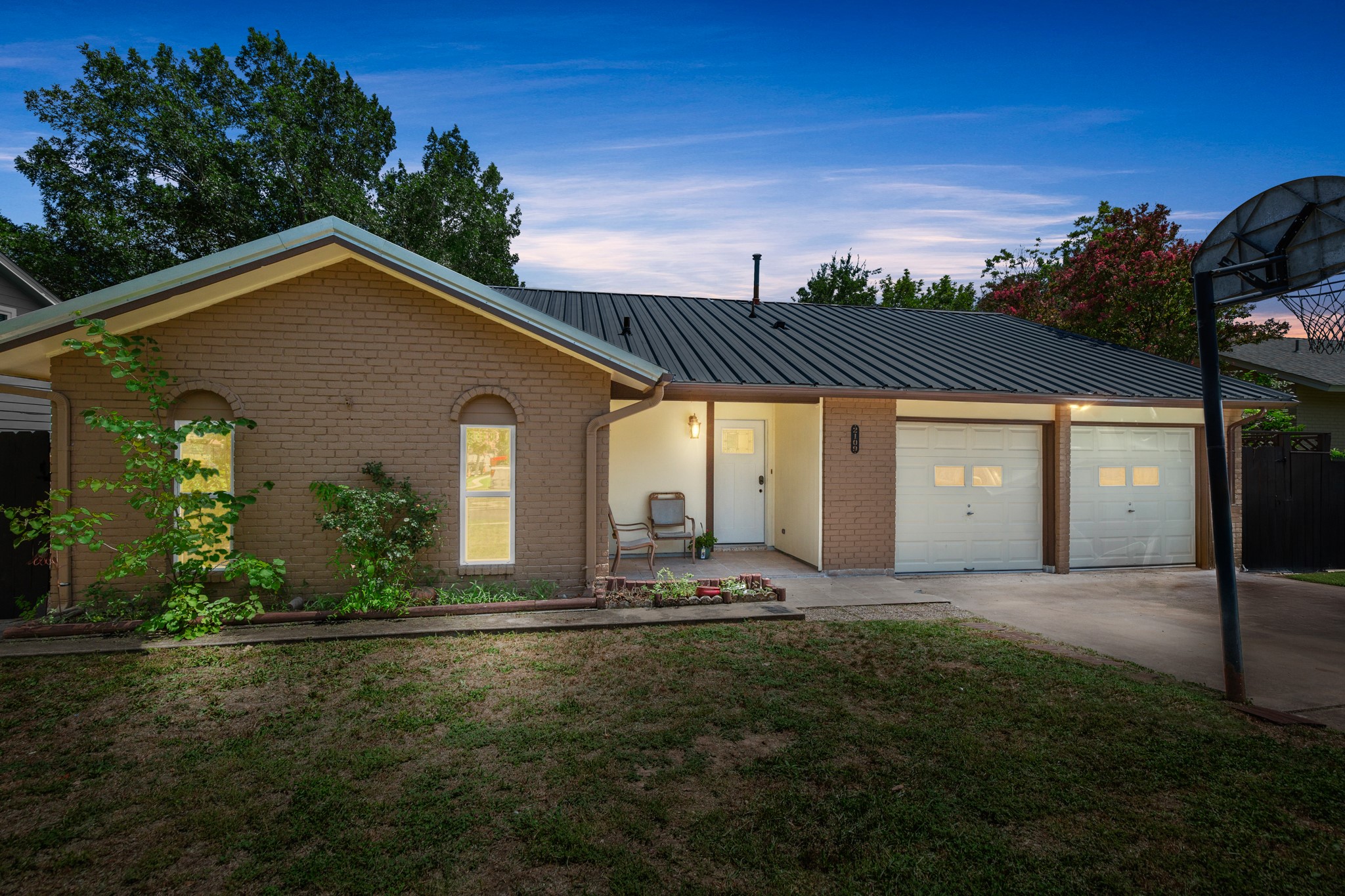 2109 Brandywine Lane Austin, TX 78727 - Photo 26 of 27 Ranch-style home featuring an attached garage, concrete driveway, brick siding, and a metal roof