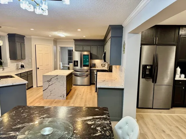 a living room with stainless steel appliances furniture a rug and a kitchen view