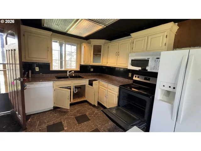 a kitchen with stainless steel appliances kitchen island granite countertop a sink refrigerator and cabinets