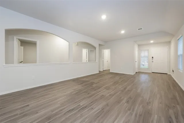 an empty room with wooden floor and windows