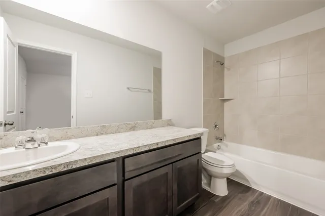 a bathroom with a granite countertop bathtub sink vanity mirror and toilet