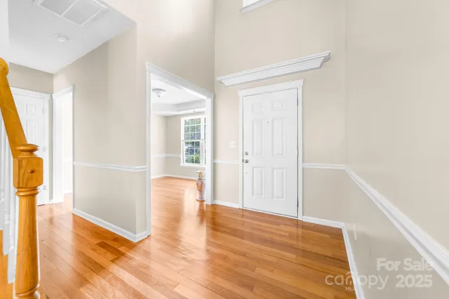 a view of a hallway with wooden floor and a bathroom