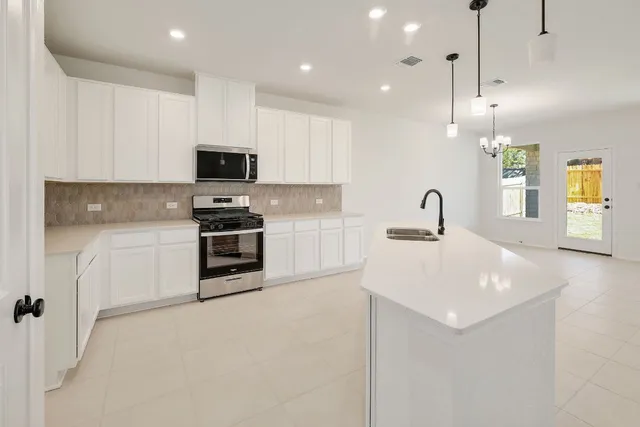 a kitchen with a sink a white cabinets and stainless steel appliances