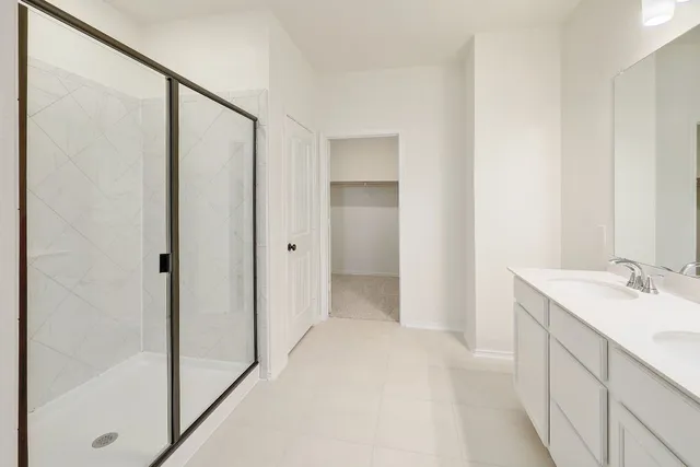 a spacious bathroom with a double vanity sink a mirror and a shower