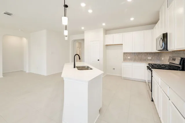 a kitchen with a sink a stove a refrigerator and white cabinets