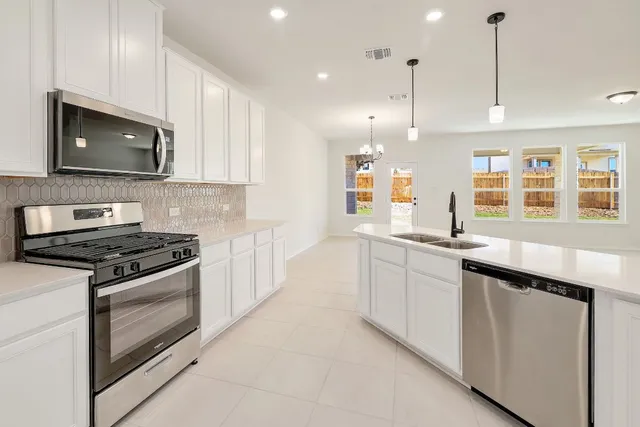 a kitchen with stainless steel appliances granite countertop a stove a sink and a microwave