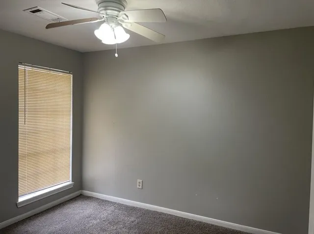 an empty room with a window and a fan