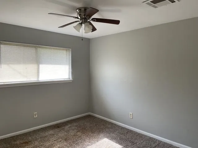 an empty room with a window and a fan