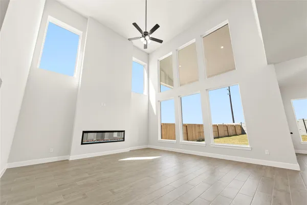 a view of an empty room with wooden floor and a ceiling fan