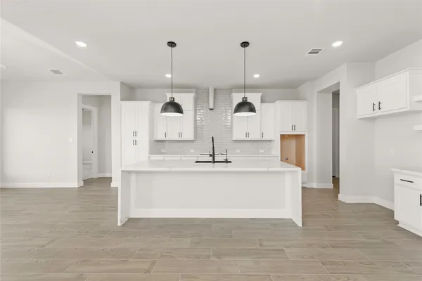 a large kitchen with a large counter top a sink stainless steel appliances and cabinets
