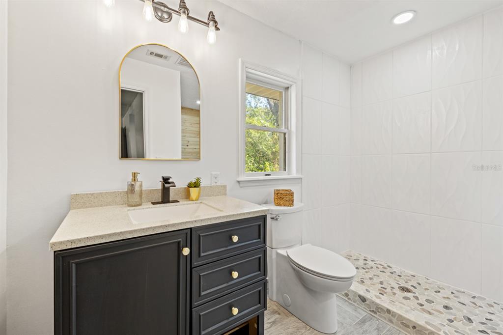 12414 Fort King Road Dade City, FL 33525 - Photo 33 of 60 a bathroom with a toilet a sink a mirror a window and vanity