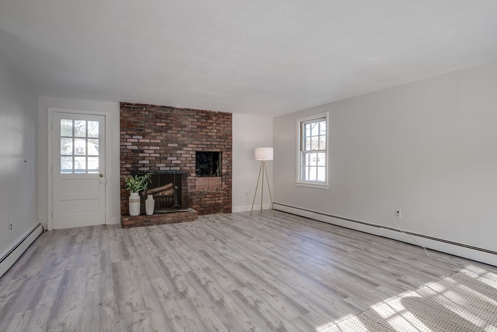 76 Brook Trail Road Concord, MA 01742 - Photo 14 of 33 an empty room with windows fireplace and wooden floor