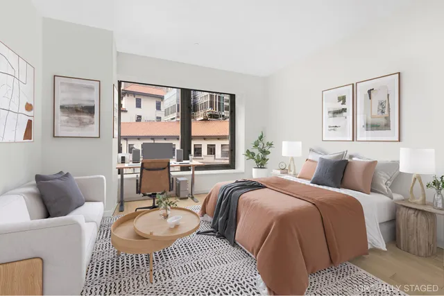 a bed room with a bed a couch and a large window