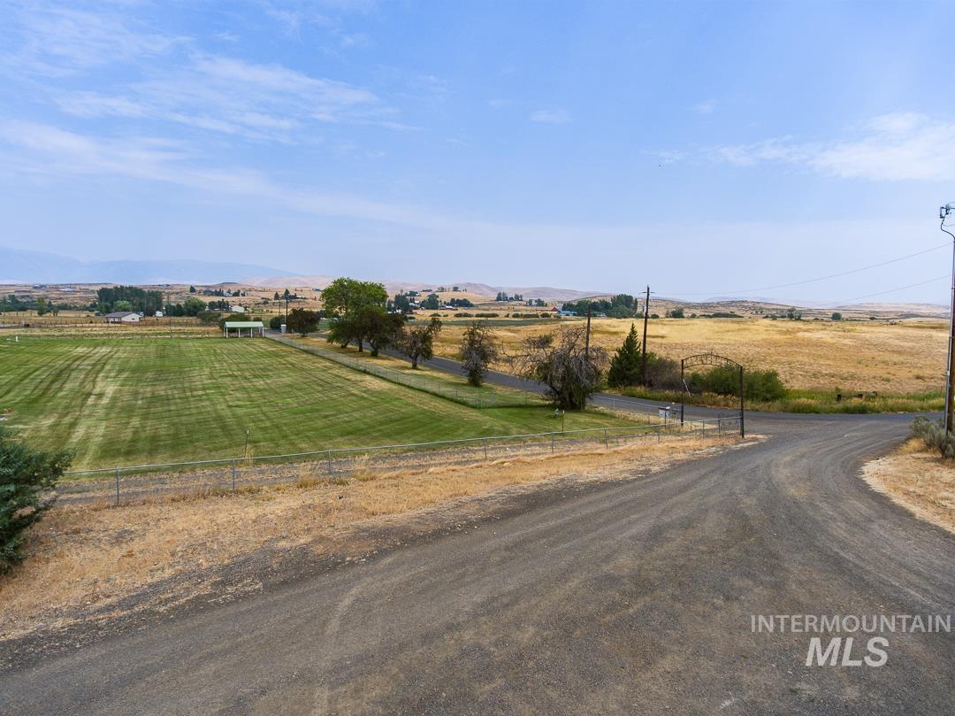 595 Cemetery Road Cambridge, ID 83610 - Photo 2 of 47 Gravel driveway, expansive green lawn, and distant agricultural fields