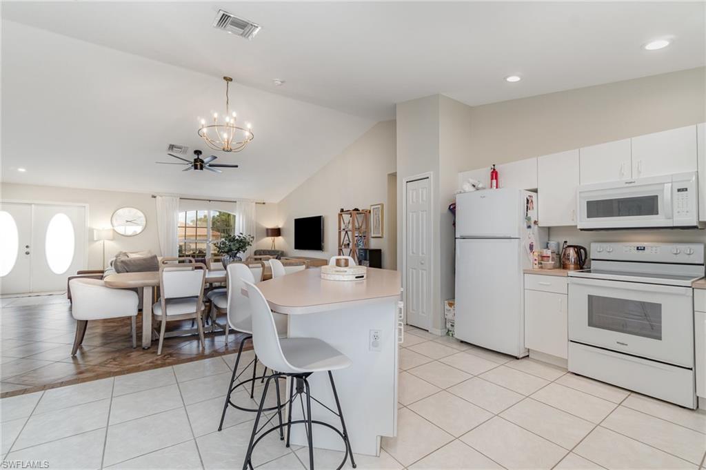 879 Rue Labeau Circle Fort Myers, FL 33913 - Photo 5 of 27 a kitchen with a refrigerator a dining table and chairs