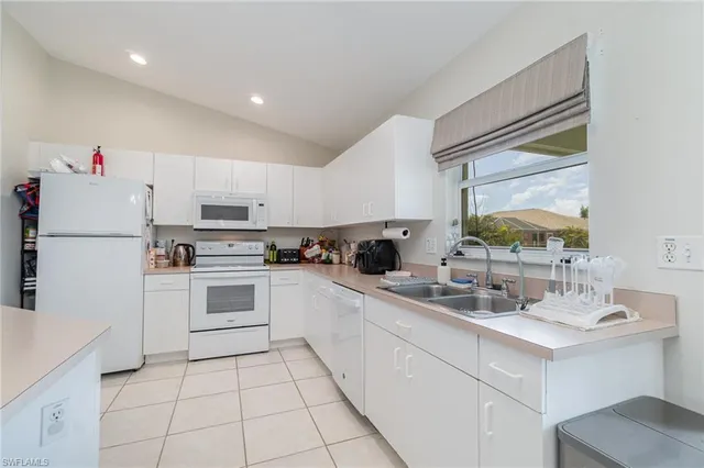 a kitchen with a sink white cabinets and white appliances