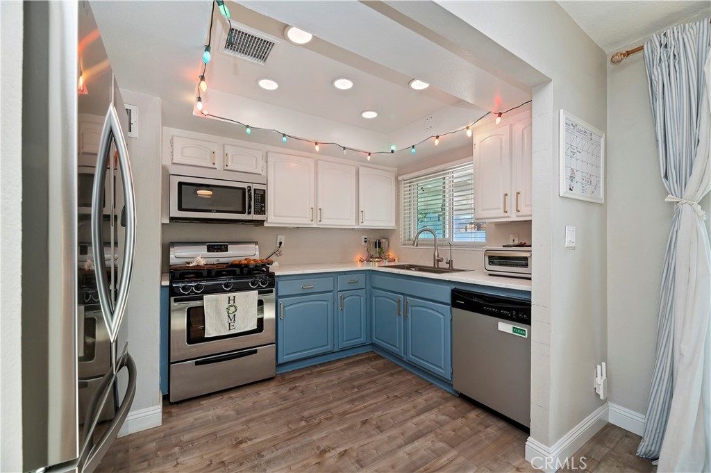 25143 Sugar Hill Road Moreno Valley, CA 92553 - Photo 12 of 28 a kitchen with kitchen island granite countertop a stove top oven a sink and dishwasher a refrigerator with wooden floor