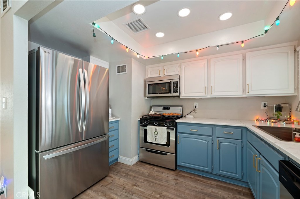 25143 Sugar Hill Road Moreno Valley, CA 92553 - Photo 14 of 28 a kitchen with stainless steel appliances granite countertop a refrigerator a stove a sink and white cabinets with wooden floor