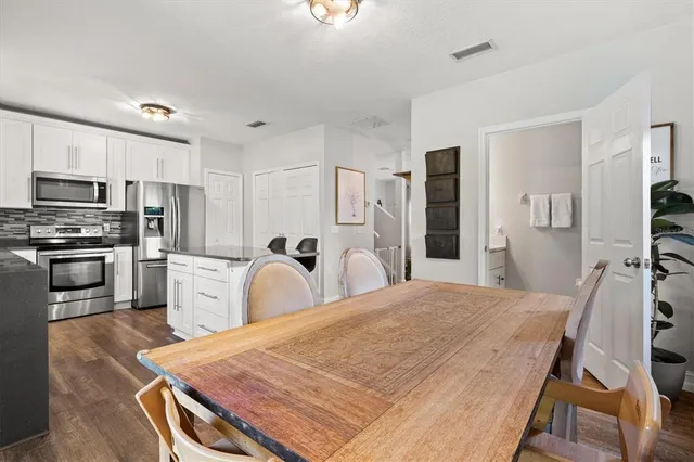 a kitchen with stainless steel appliances granite countertop a sink refrigerator dining table and chairs