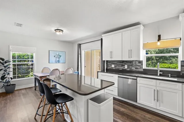 a kitchen with stainless steel appliances granite countertop a stove top oven a sink a dining table and chairs with wooden floor