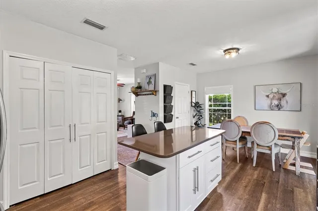 a large white kitchen with a lot of white cabinets and wooden floor