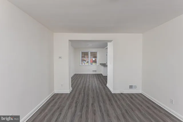 an empty room with wooden floor and a window