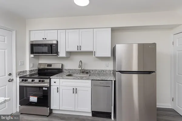 a kitchen with cabinets stainless steel appliances and a wooden floor