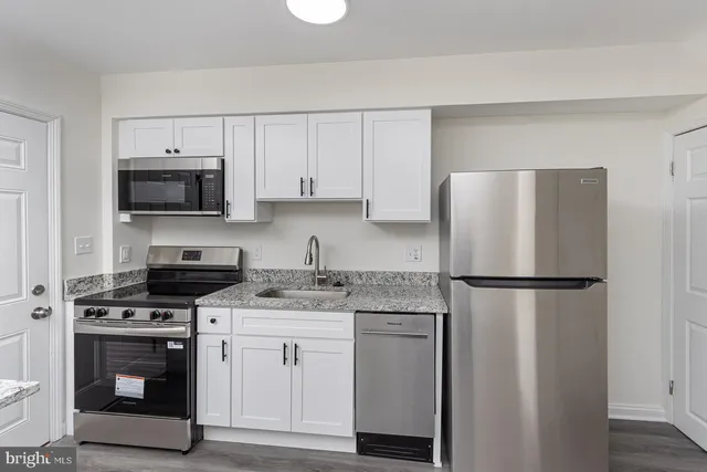 a kitchen with cabinets stainless steel appliances and a wooden floor